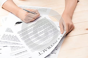 Businesswoman signing contract documents sitting at table