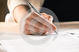 Businesswoman signing contract documents sitting at table