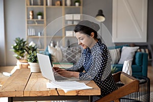 Businesswoman sit at desk in modern room texting on laptop