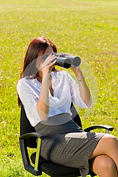 Businesswoman sit in sunny meadow seek binocular