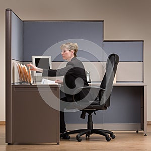 Businesswoman sitting at desk in cubicle