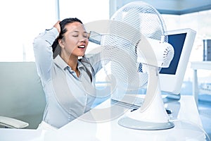 Businesswoman sitting in front of fan