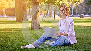 Businesswoman sitting grass summer park using laptop Business person working remote. Outdoor