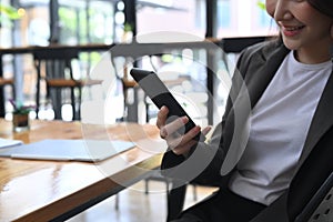 Businesswoman sitting at her office desk and using smart phone.