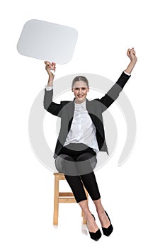 Businesswoman sitting and holding speech bubble with enthusiasm