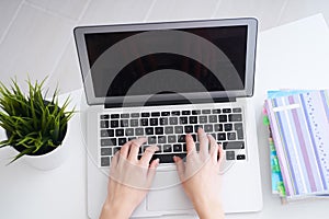 Businesswoman sitting at office desk and typing on a laptop hands close up. View from above.