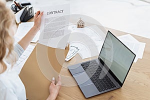 Businesswoman sitting in office, holding contract in hands