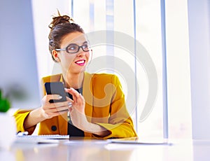 Businesswoman sitting in office with laptop on telephone