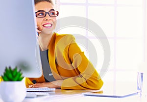 Businesswoman sitting in office with laptop on telephone