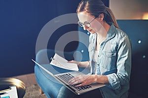 Businesswoman sitting on a sofa working online and reading documents