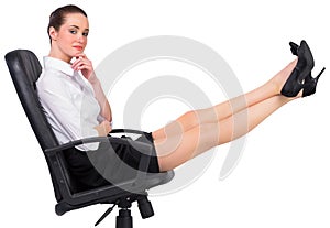 Businesswoman sitting on swivel chair with feet up photo