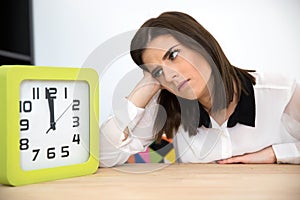 Businesswoman sitting at the table with clock