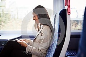 Businesswoman Sitting In Train Commuting To Work Checking Messages On Mobile Phone