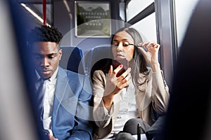 Businesswoman Sitting In Train Commuting To Work Putting On Make Up