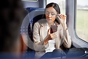 Businesswoman Sitting In Train Commuting To Work Putting On Make Up