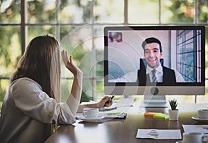 Businesswoman sitting and working in conference meeting room, looking and greeting businessman colleague on video call. Concept of