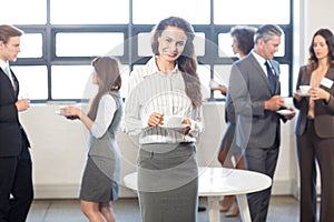 Businesswoman smiling at camera while her colleagues standing in background