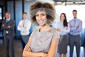 Businesswoman smiling at camera while her colleagues standing in background