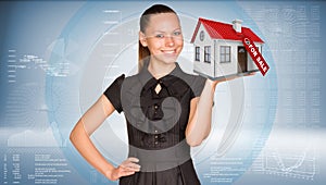 Businesswoman smiling and holding house in hand