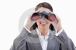 Businesswoman smiling and looking through binoculars