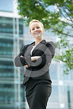 Businesswoman smiling outdoors with arms crossed