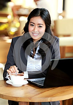 Businesswoman smiling while stirring a coffee