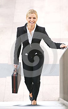 Businesswoman smiling and walking upstairs with briefcase