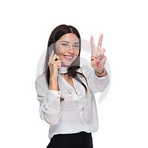 Businesswoman speaking on the phone and making peace sign