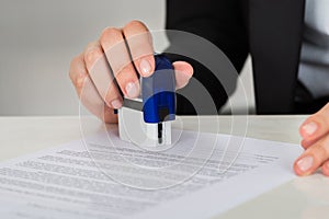 Businesswoman Stamping Contract Document At Desk