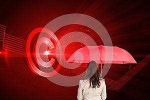 Businesswoman standing back to camera holding red umbrella