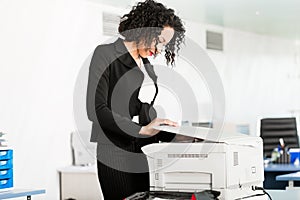 Businesswoman standing at the copying machine photo