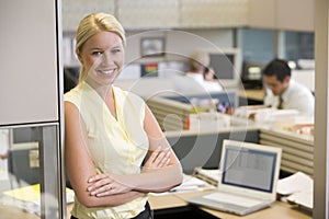 Businesswoman standing in cubicle smiling