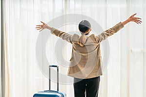 Businesswoman standing by hotel room window feeling happy