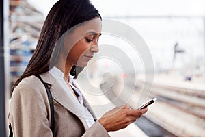 Businesswoman Standing On Railway Platform Commuting To Work Booking Ticket On Mobile Phone