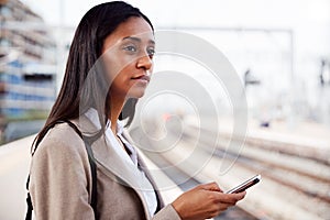 Businesswoman Standing On Railway Platform Commuting To Work Booking Ticket On Mobile Phone