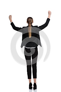 Businesswoman standing with raised hands and victorious in rear view