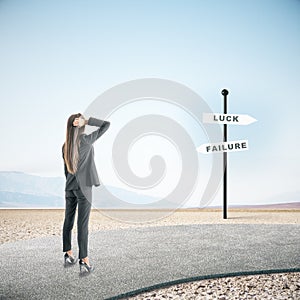 Businesswoman standing on road and looking on luck and failure sign post