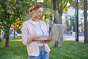 Businesswoman standing summer park using laptop Business persone working remote. Outdoor photo