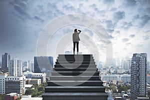 Businesswoman standing at the top of the concrete staircase watching at the cityscape thinking. Future success and leadership