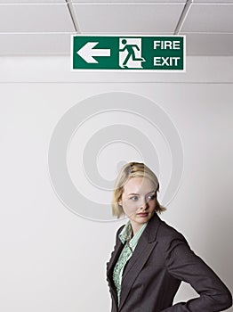 Businesswoman Standing Under Exit Sign
