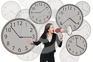 Businesswoman stands among clocks.