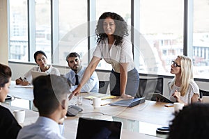 Businesswoman Stands To Address Meeting Around Board Table