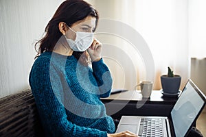 Businesswoman stays home and works during coronavirus epidemia quarantine. Female worker touches her medical mask and typing on a photo
