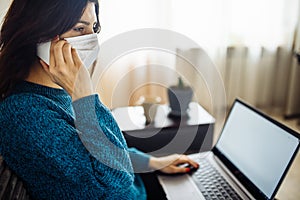 Businesswoman stays home and works during coronavirus epidemia quarantine. Female worker wearing a medical mask and typing on a