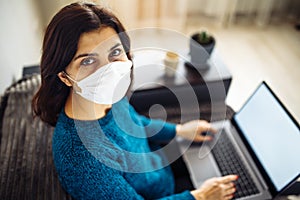 Businesswoman stays home and works during coronavirus epidemia quarantine. Female worker wearing a medical mask and typing on a