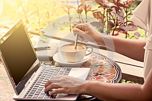 Businesswoman stirred coffee in the cup and type on laptop