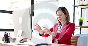 Businesswoman stretches hands forward and continues to work on computer