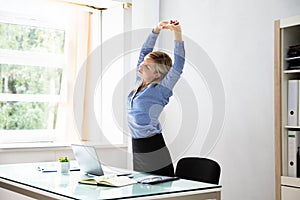 Businesswoman Stretching Her Arms At Workplace photo