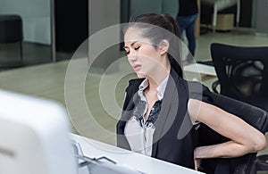 Businesswoman suffering from back pain in office