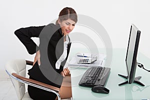 Businesswoman suffering from backache at computer desk